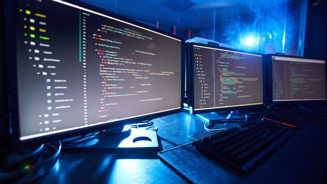 Image of computer monitors updating the software they standing on the table in dark room